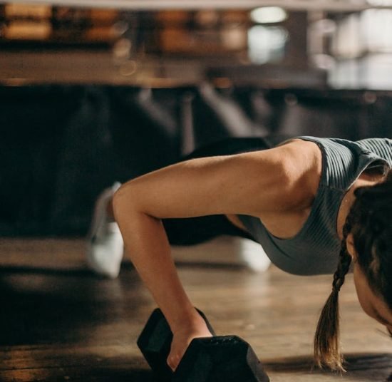 Woman in Black and White Tank Top and Black Shorts Lying on Brown Wooden Floor